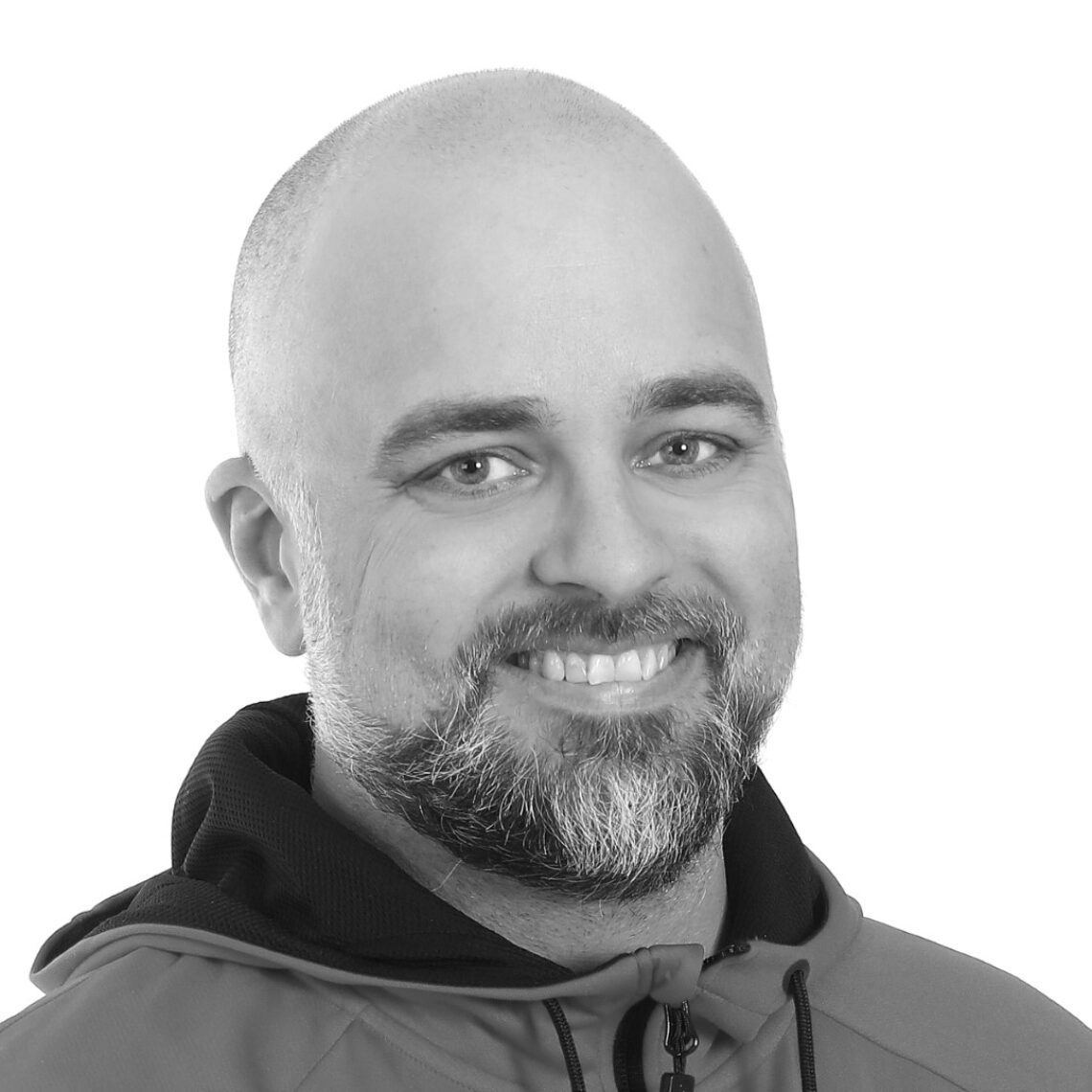 En leende man med skägg och huvtröja.